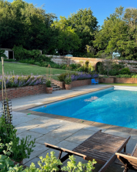 A woman relaxing against the side of a swimming pool