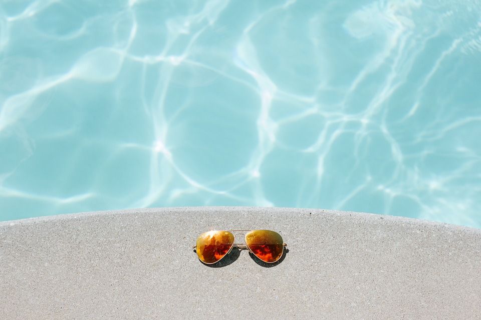 Sunglasses by the side of a swimming pool during summer