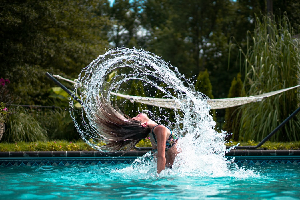 A woman flicking her hair in a swimming pool