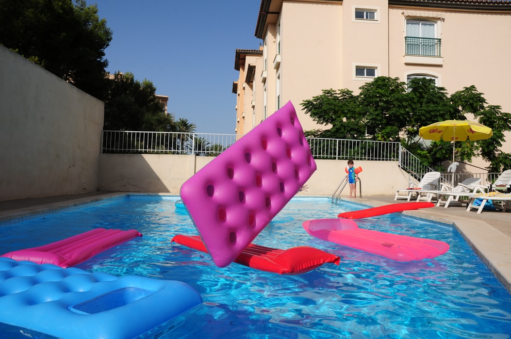 Colourful lilo inflatables being thrown into a swimming pool