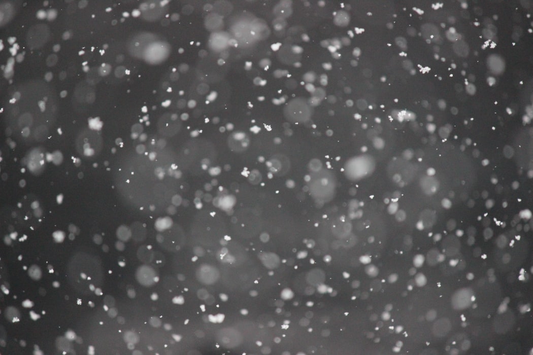 Snow falling during winter against a black background