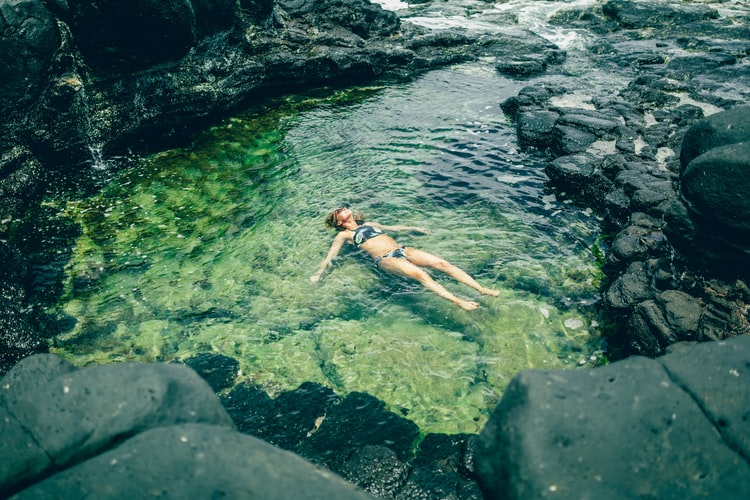 A woman swimming in a rock pool with algae