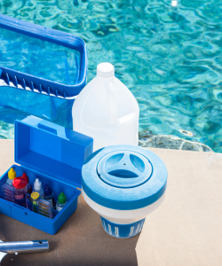 Various pool maintenance tools and chemicals by the side of a pool