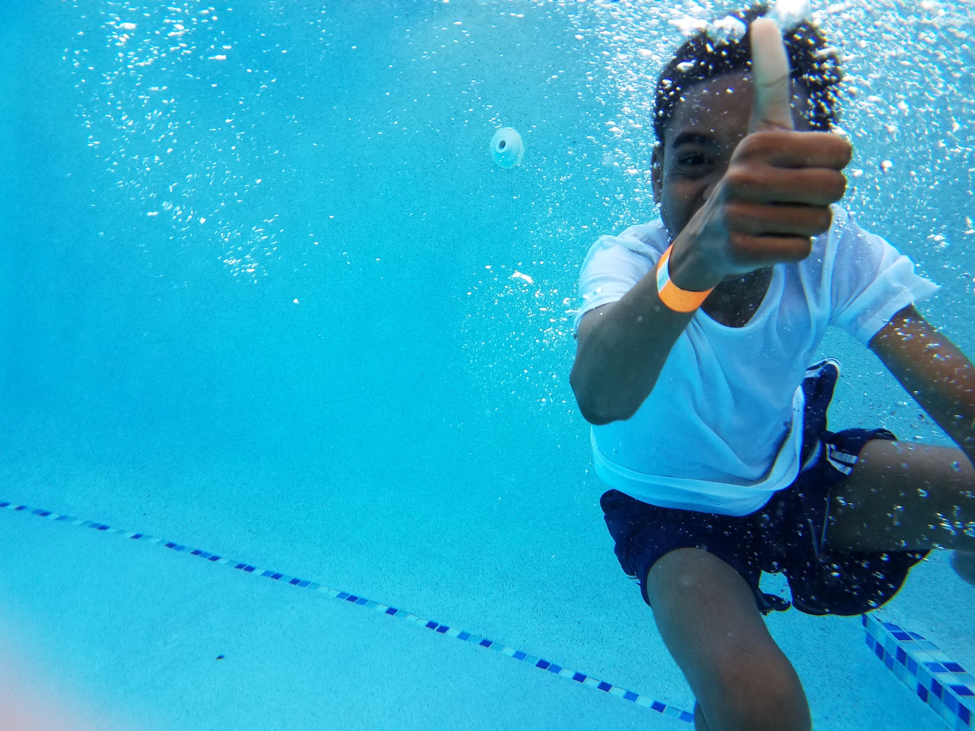 A child in a pool giving a thumbs-up